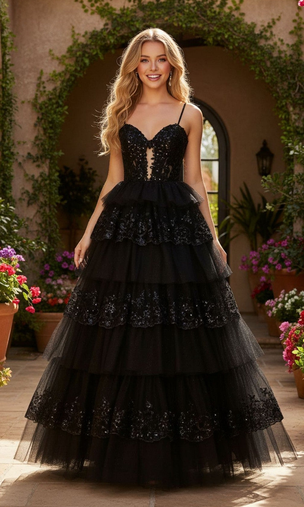 A woman stands outdoors among potted flowers and greenery, wearing the Sparkly Prom Ball Gown: PromGirl Exclusive 250074 in black, featuring a tiered skirt, illusion corset bodice, and sequin details.